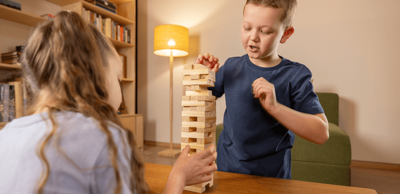 Two kids playing with stacking blocks, enjoying screen-free play and developing fine motor and problem-solving skills with traditional toys.