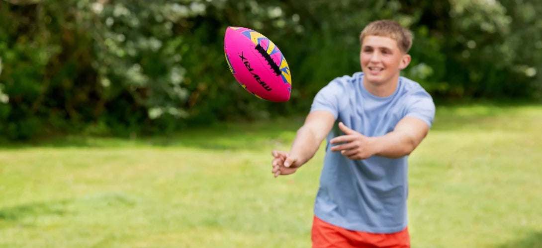a teenage boy throwing a pink neoprene American football
