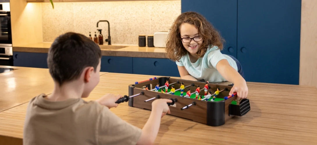 two children playing table football on a table top games table