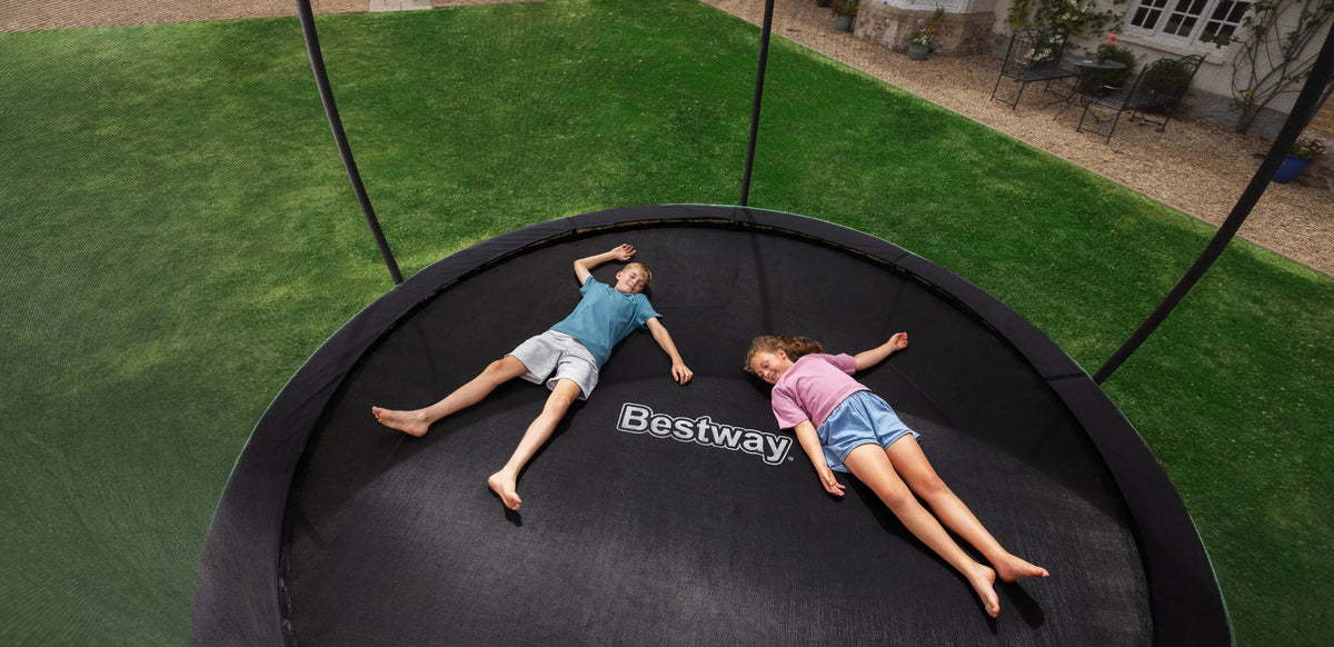 Kids playing in garden on trampoline after school to burn energy with outdoor active play