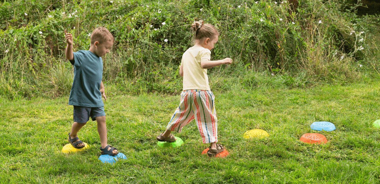 Children playing on stepping stones in a garden, engaging in active play that supports brain development, balance, and motor skills.