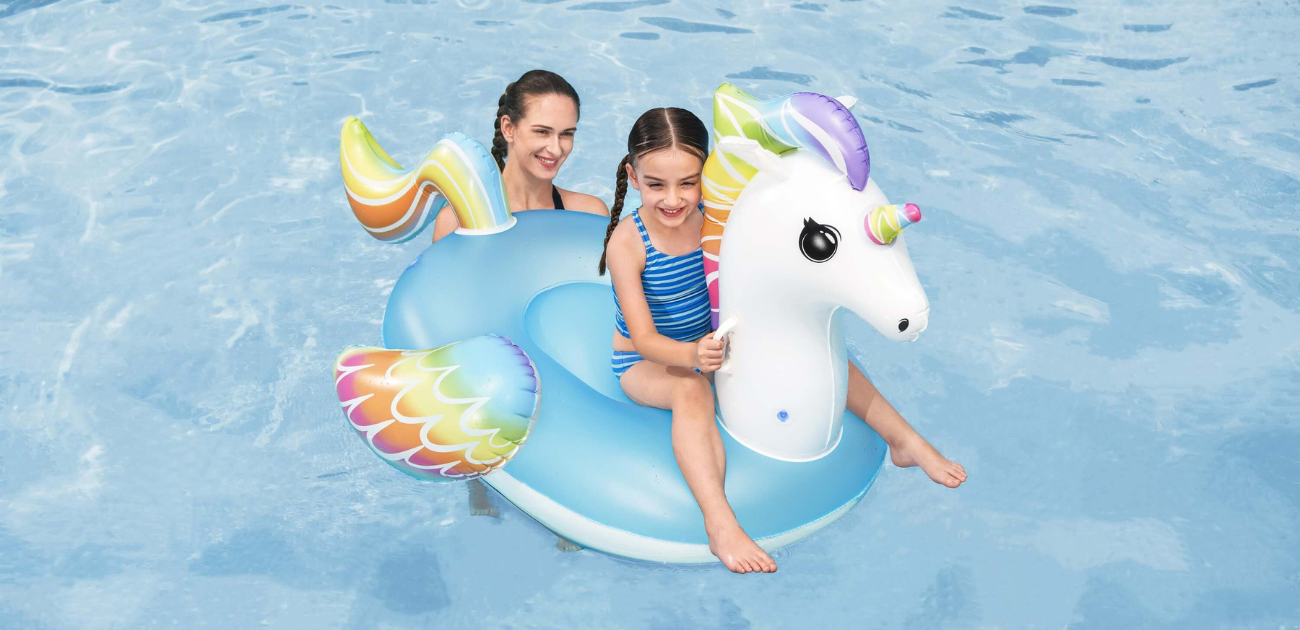 Mother and daughter relaxing on a unicorn pool float, showing the best travel toys for holidays.