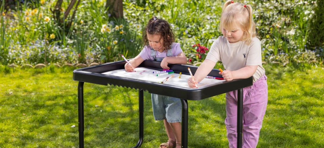 two young girls using a Play Tray in the garden to do colouring