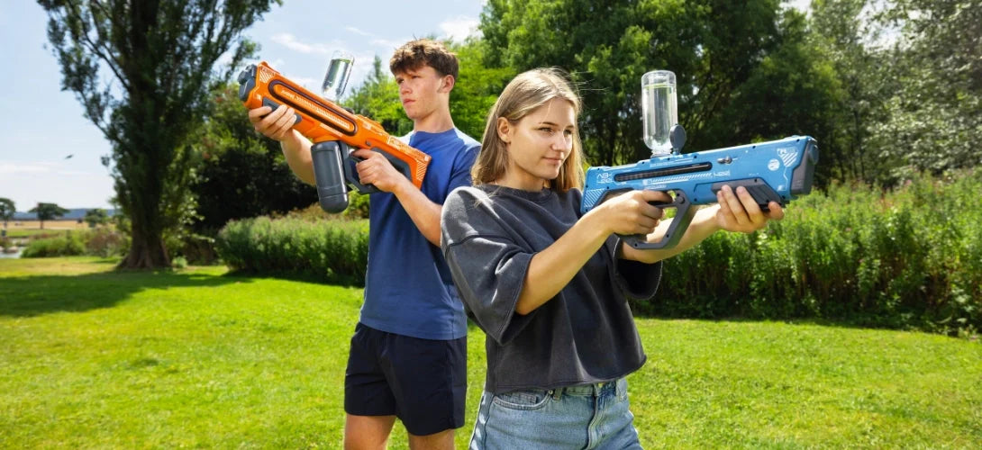 two teenage children holding water guns in a park