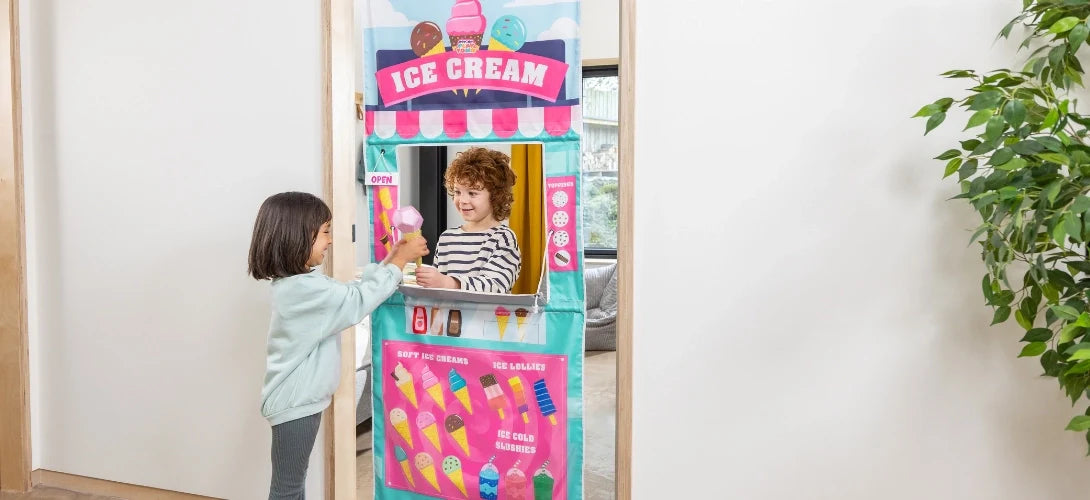 two young children playing with an ice cream themed play curtain