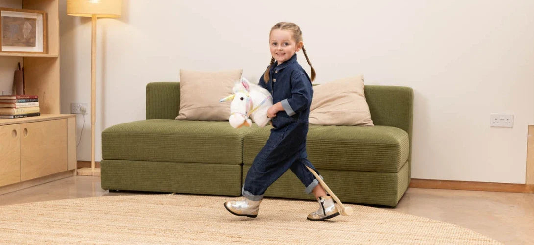 a young girl playing with a light coloured hobby horse in a lounge
