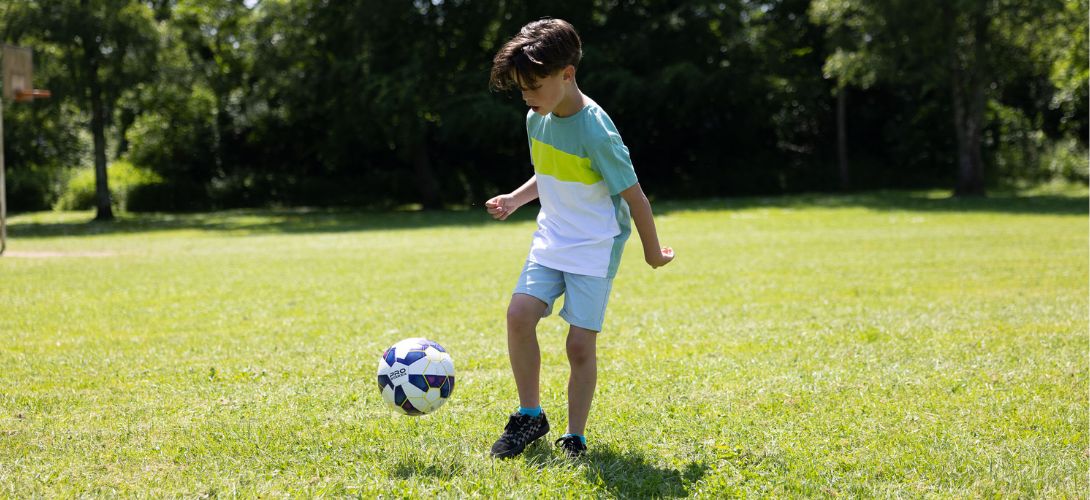 A boy playing football in a park