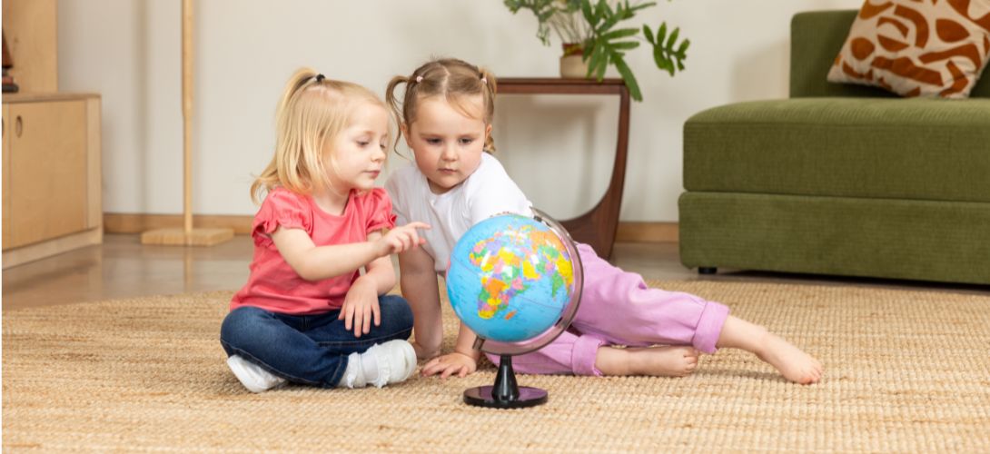 two young girls looking at a colourful globe