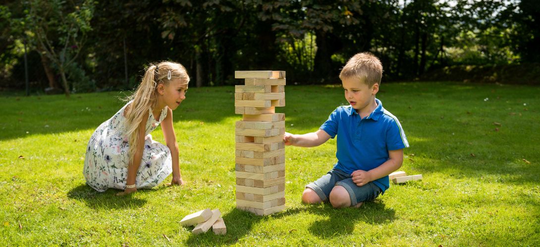 Two young children playing Stack & Fall in a garden