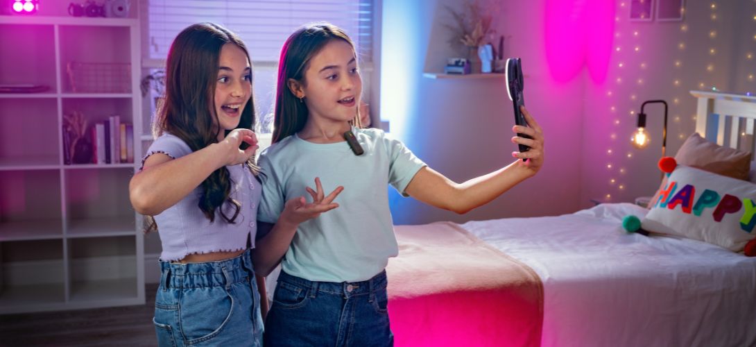 Two teenage girls in a bedroom using a mi-mic live with their phone