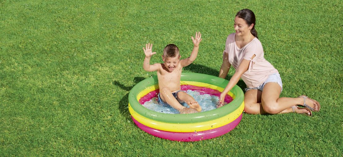 a mum and son enjoying a pink, yellow and green paddling pool