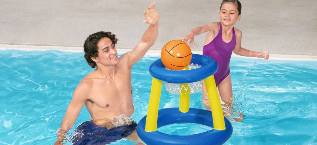 Two people playing with a floating basketball toy in a swimming pool