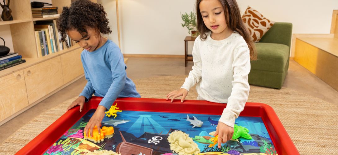 Two young children baking cookies on a black Play Tray