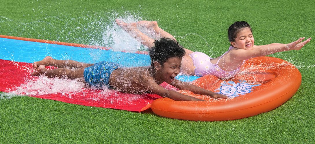 a young girl and boy playing on an orange water slide