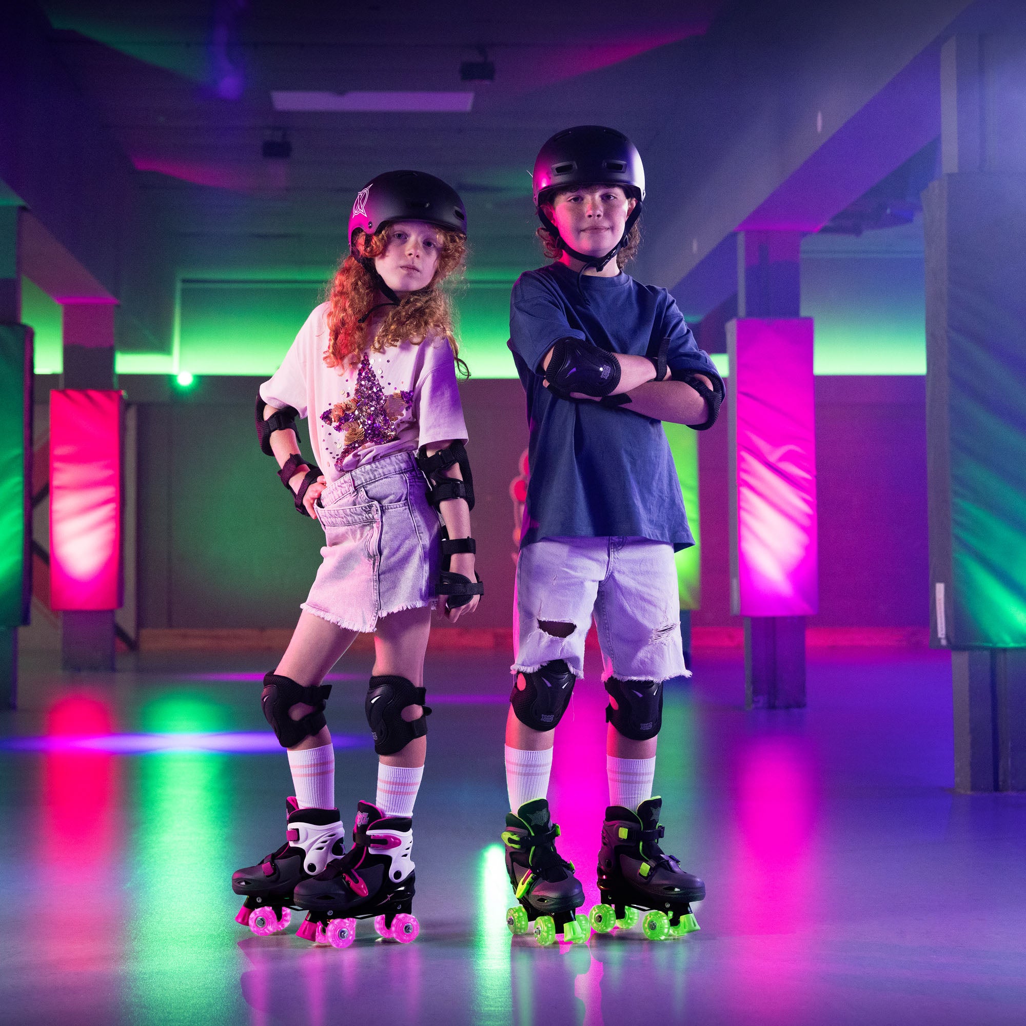 Two children on roller skates in a neon-lit indoor setting